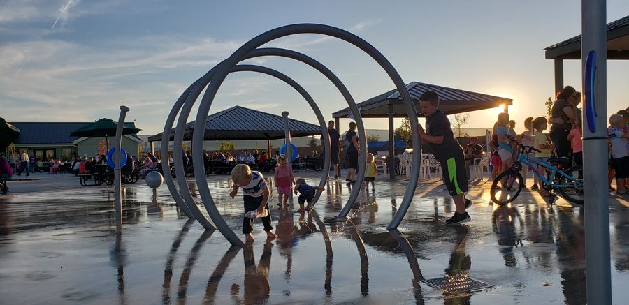 Splash pad with sculptural arches at sunset